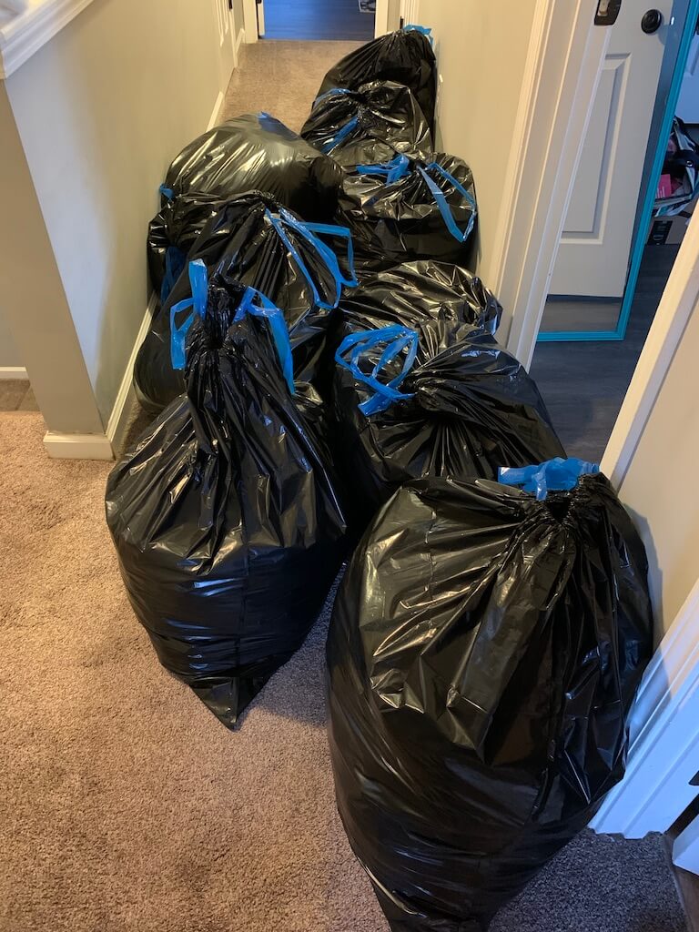 10 large black trash bags in hallway.