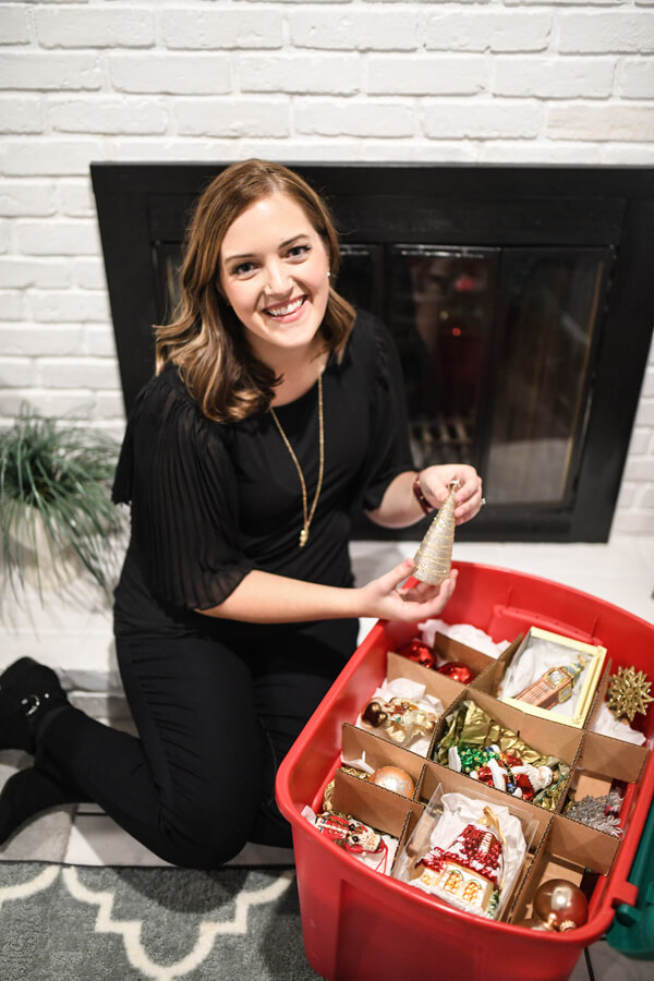 Professional organizer sitting on floor with ornament storage bin.