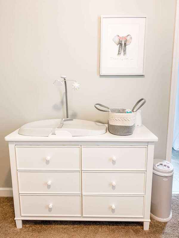 Grey nursery with white dresser and changing pad on top.