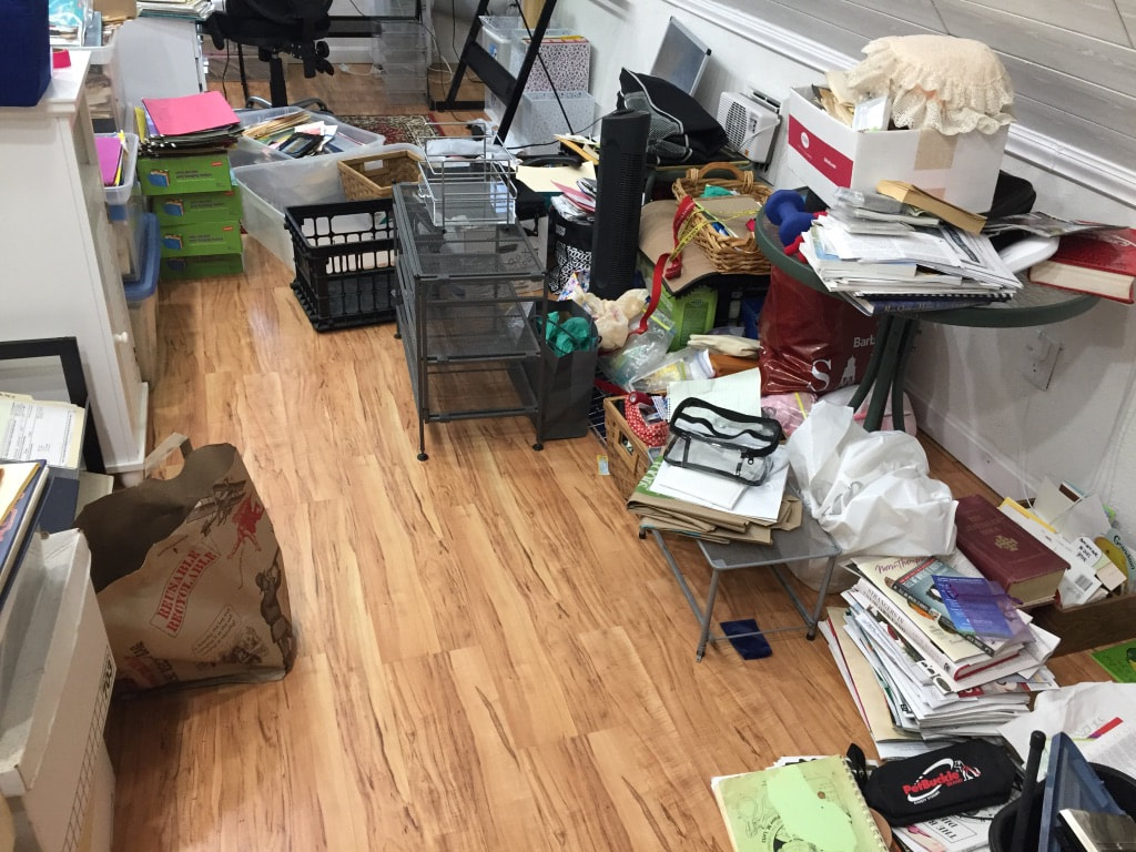 Cluttered office with stacks of paper on floor.