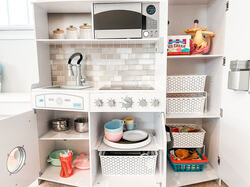 organized toy kitchen in playroom with baskets